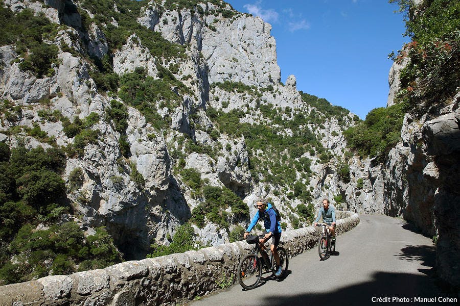 Cyclistes sur la route qui coule le long des Gorges de Galamus
