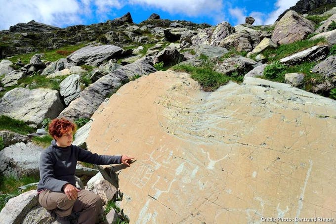 Archéologue Nicoletta Bianchi devant la roche de l'Éclat, gravée de figures corniformes et de poignards