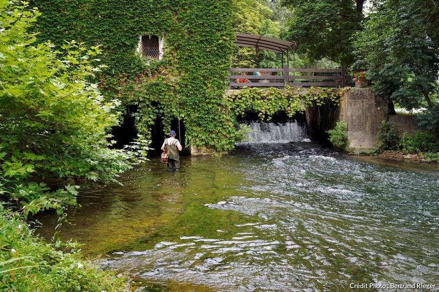 Pêcheur à la ligne au pied du moulin de Taillepetit, dans le Périgord Blanc (Dordogne)