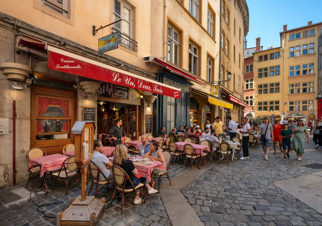 les cafés et les bâtiments anciens ocre jaune de la place Neuve- Saint-Jean, entre la rue Saint-Jean et la rue du Bœuf.
