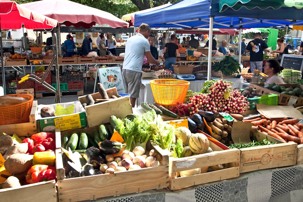 Marché de Ribérac, en plein air, avec étals de légumes frais et clients.