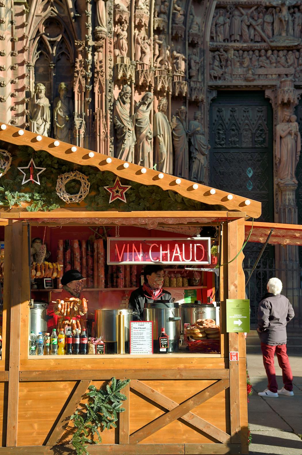 Stand de vin chaud dans un marché avec des clients et décorations de Noël.