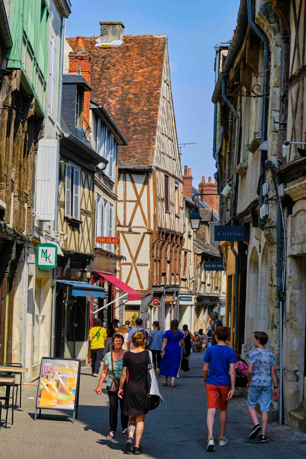 Habitants et touristes marchant dans la rue commerçante animée.