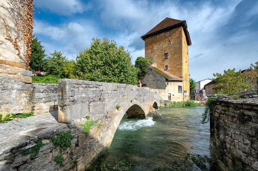 Le pont des Capucins, pont piéton du e xviii sièclesous lequel passe la rivière la Cuisance, et la tour Gloriette (xiiie- xvie-xviie siècles), ancienne tour de fortification carrée de 17 mètres de haut.