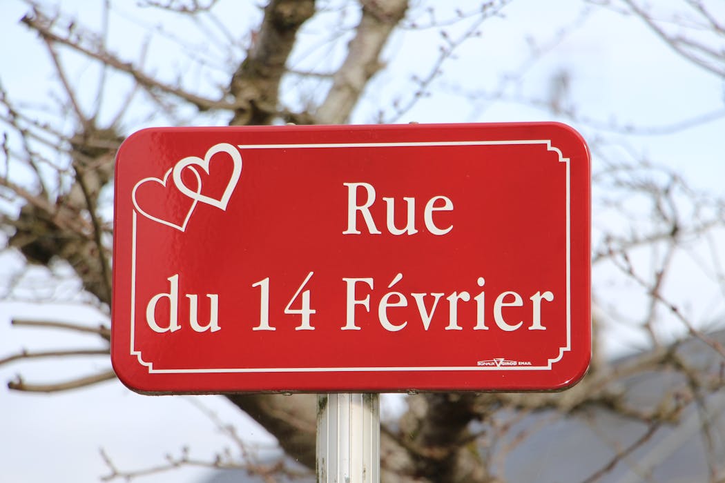 Panneau rouge indiquant la rue du 14 Février avec deux cœurs dessinés