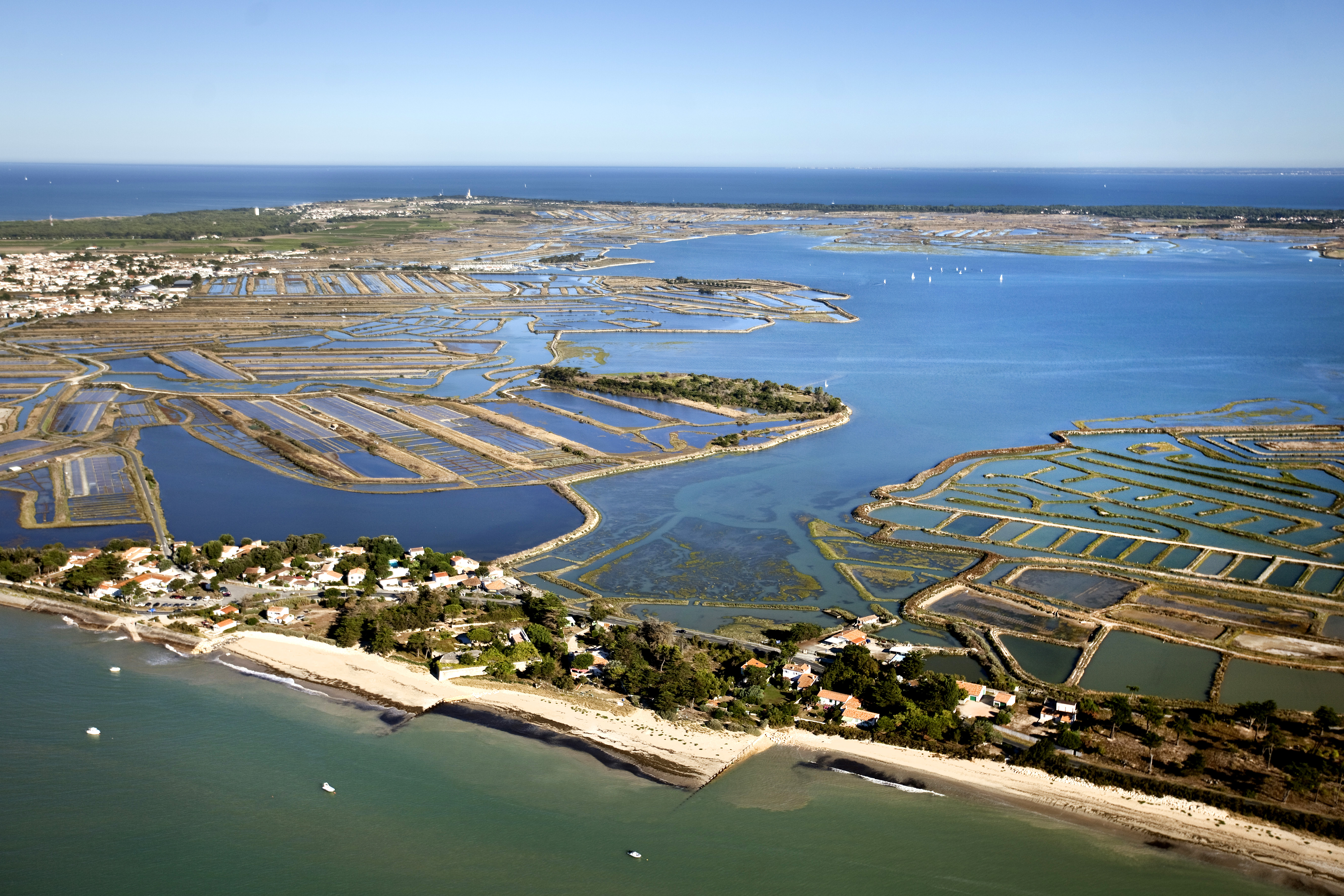 photographie aérienne de la côte : la plage de la Couarde-sur- Mer, les marais salants du Fiers d’Ars, la pointe des Baleines étendue sur 8 kilomètres, ainsi que la presqu’île des Porte-en-Ré et le Pertuis breton.