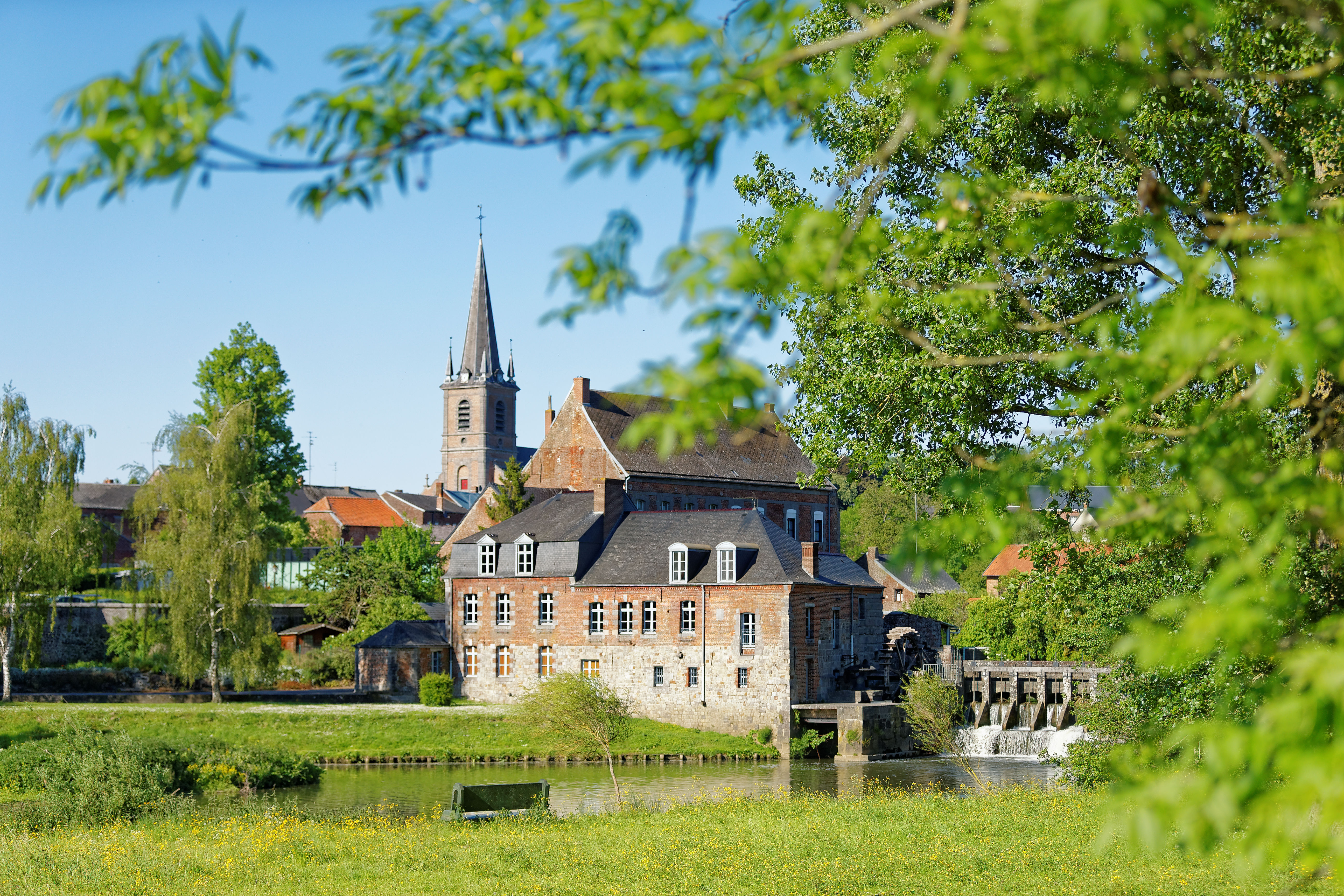 L’abbaye de Maroilles, monastère bénédiction fondé au viie siècle. Au premier plan, posé au bord de la rivière, repose le moulin à eau où les paysans venaient moudre leur grain. Les moines prélevaient la dîme qui était stockée dans la majestueuse grange dîmière (1735), autre joyau local.