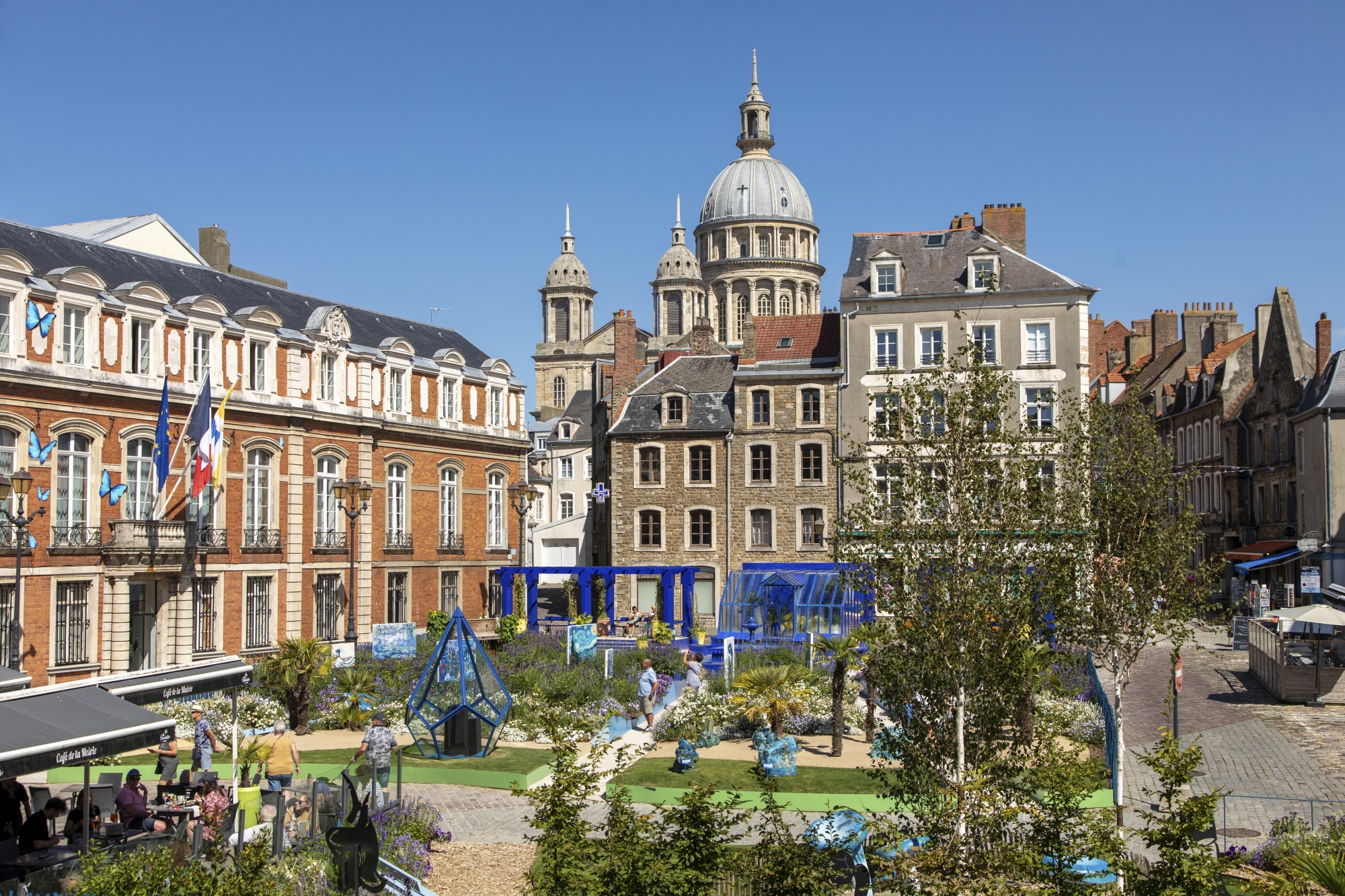 La place Godefroy-de-Bouillon, qui accueille chaque été un jardin éphémère (ici la 17e édition, baptisée « Rhapsody in Blue »), devant l’hôtel de ville, bâtisse en briques rouges du xviie, et le beffroi médiéval (XIIe), ancien donjon roman inscrit au patrimoine mondial de l’Unesco.